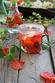 Glass votive holder decorated with poppies and strawberry vines, between lady's mantle