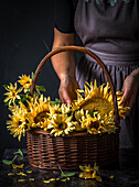 Sonnenblumen in einem Korb, Frau im Hintergrund