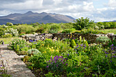 Landhausgarten mit Blumenbeeten und Sitzgruppe, Wege und Gartenmauern aus Feldsteinen