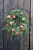 A wreath of apples and grass on a wooden wall