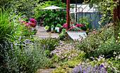 Blühender Garten mit Hängematte, Sonnenschirm und Kiesweg