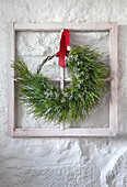 Christmas wreath on white window frame with red ribbon