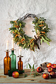 Advent wreath with orange slices and candles in bottles on a wooden table with apples