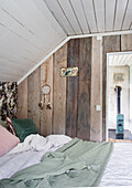 Schlafbereich mit Holzwand und Kaminofen in rustikalem Ambiente