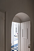 White archway and wooden door, view of tiled courtyard