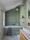 Shower and bath in bathroom with green tiles and marble cladding