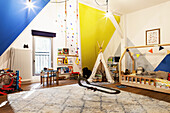 Kinderzimmer mit farbigen Wänden, Tipi-Zelt, Kinderbett und flauschigem Teppich