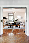 Dining room with black chairs and wooden table, herringbone parquet flooring, Sputnik lamp