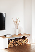 Firewood storage under shelf with a vase in white living room
