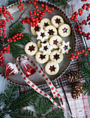 Old baking tin filled with Swiss jam cookies, glass ornaments, and holly berries