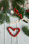 Silver spoon with holly bouquet and Christmas ribbon, heart shape made of holly berries