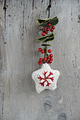 Garland with knitted star, holly berries and holly leaves
