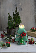 Candle in the shape of a fir tree, decorated with holly berries and Christmas tree pendant