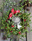 Birdseed in a jar, surrounded by a mistletoe wreath with rose hips and cones