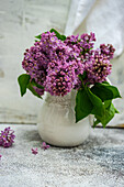 Purple lilac bouquet in a white pitcher