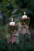 Garden candle stakes decorated with moss, candles, and paper stars