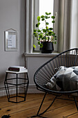 Side table and chair in the corner of a room with plant on the windowsill