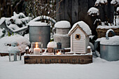 Lanterns and nesting boxes on a snow-covered wooden box on a terrace
