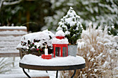 Winterdekoration mit Kerzen auf einem eingeschneiten Gartentisch