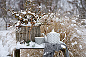 A tea set on a snow-covered wooden box in a garden
