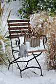 Basket with larch branches on a snowed-in garden chair