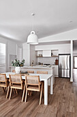 A modern Scandi style open plan kitchen and lounge room with plantation shutters. The kitchen has v groove panelling, gold tapware and white joinery. The flooring is oak.