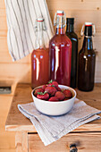 Fresh strawberries and home-made syrup on a wooden cupboard