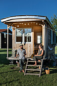 Extended caravan with wooden panelling, couple sitting on the terrace