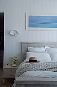 Mango wood queen bed against white painted wood paneling in bedroom