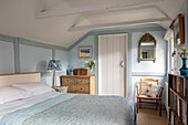 Queen bed and chest of drawers in a bedroom colored in light blue and white