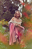 Young woman with blanket made of recycled fibers in pink, peach and cream colors