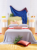 Doppelbett mit hohem Betthaupt, darüber Überwurf in hellem Schlafzimmer