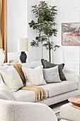 Living room with grey sofa with throw pillows and a potted tree
