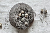 Nest made of tumbleweed with naturally dyed Easter eggs on ceramic plate