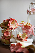 Stoffbänder mit Kunstblüten um Glasgefäßen