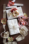 Geschenke in weißer Verpackung mit Stoffbändern und Kunstblüten