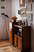 Black and white photos glued to the back of picture frames, antique cabinet, and tripod lamp
