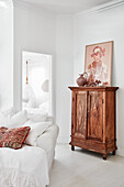 Sofa with white linen cover and antique cupboard in ethnic style in the living room