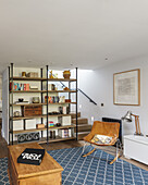 Open shelf next to staircase, leather rocking chair and wooden chest in living room