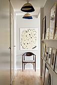 Schmaler Flur mit Bildersammlung, Stuhl unter abstrakter Kunst