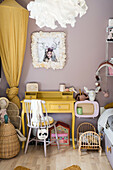 Yellow bed canopy, desk in matching color, painting with artisan frame above it in the girls' room