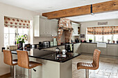 Bright fitted kitchen cabinets across the corner in a country style, kitchen peninsula counter with bar stools