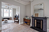 Fireplace with mirror and wooden cupboard in room with light grey walls and stucco work