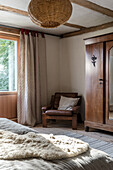 Leather armchair next to wardrobe in country-style bedroom