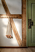 Net produce bag on old exposed post and beam wall next to a green door