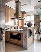 Carved 17th century oak figurine in modern kitchen with stainless steel range hood