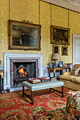 Paintings in gold frames, fireplace, and upholstered furniture in a country house