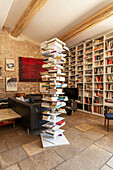 Free-standing shelf with books and wall of books in open plan living area