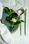 Gardenienzweig mit weißer Blüte auf dem gedeckten Tisch