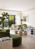Organically shaped couch with green upholstery and vintage marble table in a bright living room